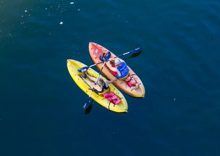 Two colorful kayaks floating on bright blue water, viewed from above.